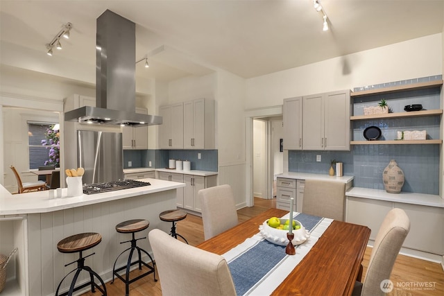 kitchen with track lighting, island exhaust hood, a breakfast bar, and light countertops