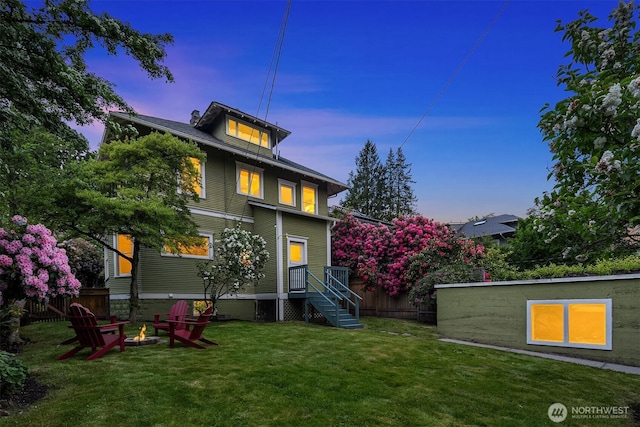 back of property with a yard and a fire pit
