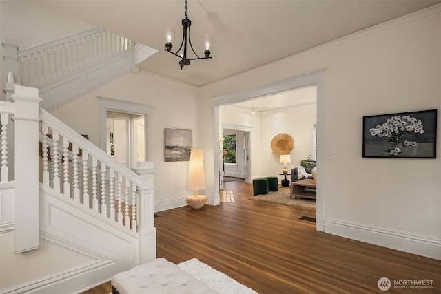 staircase with wood finished floors, baseboards, and a chandelier