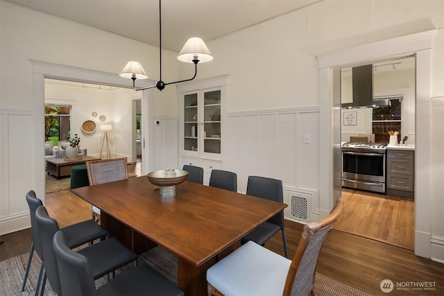 dining room featuring wood finished floors, a wainscoted wall, and a decorative wall