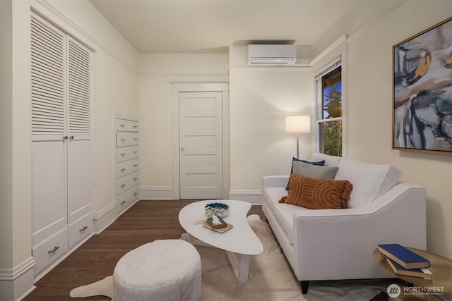 living area with an AC wall unit and wood finished floors
