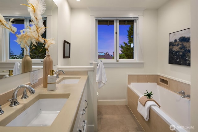 full bath with a garden tub, tile patterned flooring, double vanity, and baseboards
