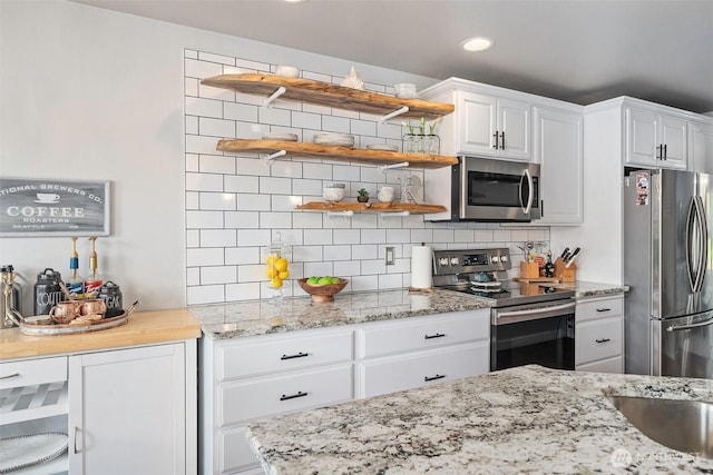 kitchen with appliances with stainless steel finishes, tasteful backsplash, light stone counters, recessed lighting, and white cabinetry