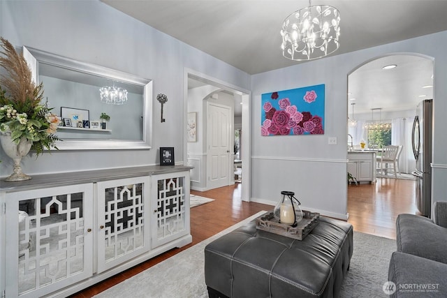 living room with arched walkways, wood finished floors, and a chandelier