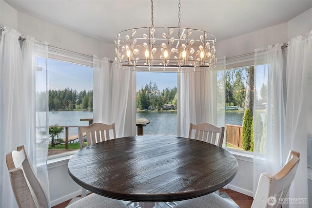 dining space with a water view, baseboards, a chandelier, and wood finished floors