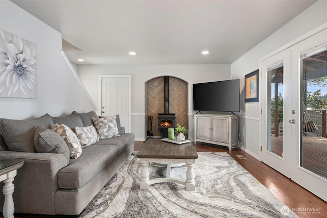 living room featuring a wood stove, french doors, recessed lighting, and wood finished floors