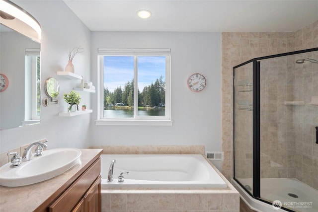 bathroom featuring visible vents, a shower stall, a bath, and vanity