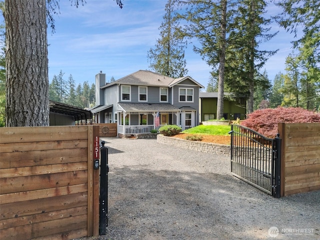 view of front of home featuring a gate, covered porch, a chimney, and driveway