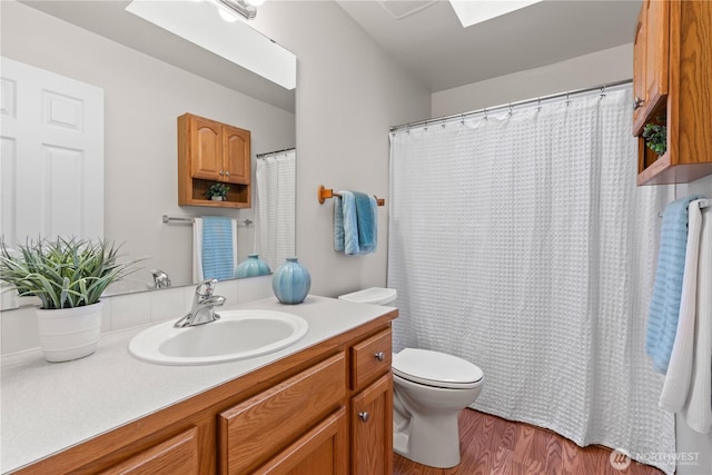 710 122nd Avenue Ct E, Edgewood, WA 98372 - bathroom with a skylight, vanity, toilet, and wood finished floors