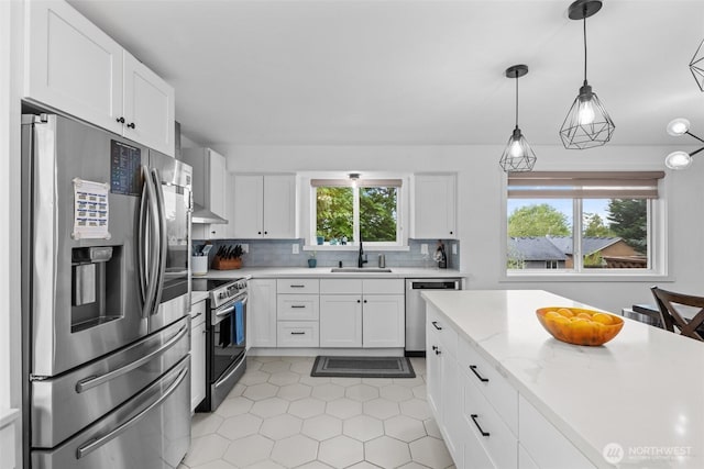 kitchen featuring light tile patterned flooring, a sink, stainless steel appliances, white cabinetry, and backsplash