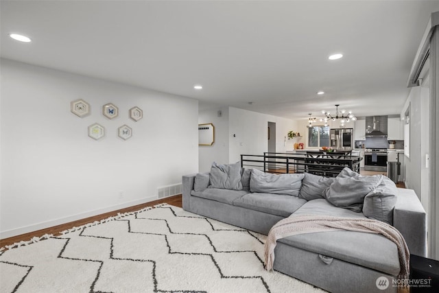 living room featuring a chandelier, visible vents, wood finished floors, and recessed lighting