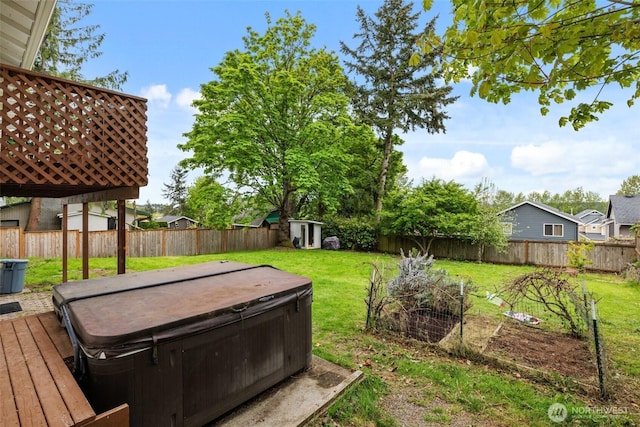 view of yard with a wooden deck, a hot tub, an outdoor structure, a fenced backyard, and a storage unit