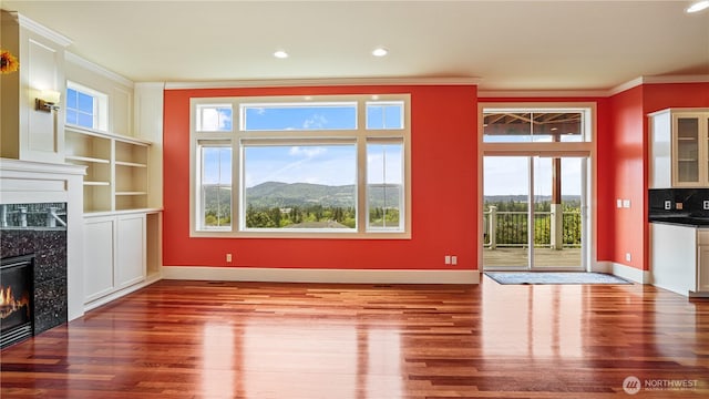 unfurnished living room featuring crown molding, wood finished floors, baseboards, recessed lighting, and a high end fireplace