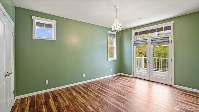 unfurnished dining area featuring baseboards, a notable chandelier, wood finished floors, and visible vents