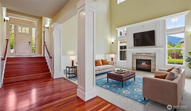 living room with a glass covered fireplace, plenty of natural light, wood finished floors, and stairway