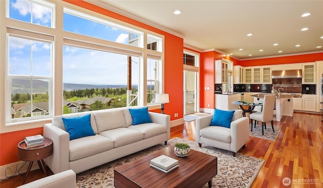 living area featuring crown molding, recessed lighting, baseboards, and light wood-style flooring