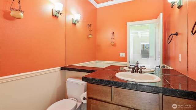 half bathroom featuring crown molding, toilet, and vanity