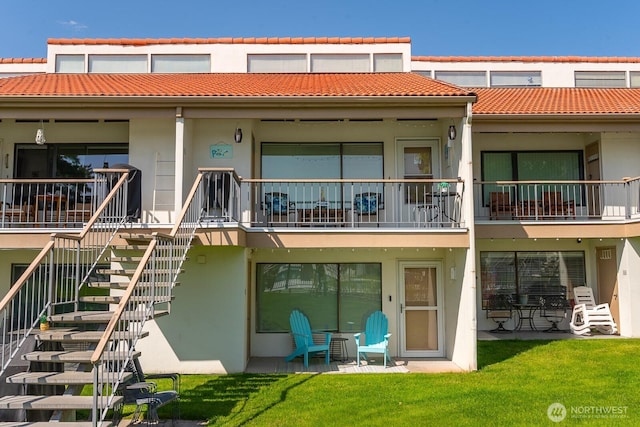 rear view of house with stairway, a lawn, a patio, and stucco siding