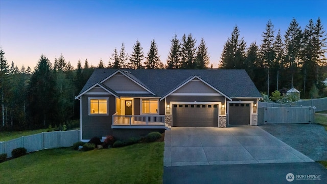 craftsman-style home with a front lawn, fence, stone siding, concrete driveway, and an attached garage