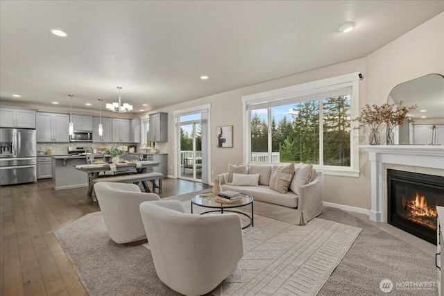 living area with recessed lighting, dark wood finished floors, a chandelier, and a tile fireplace