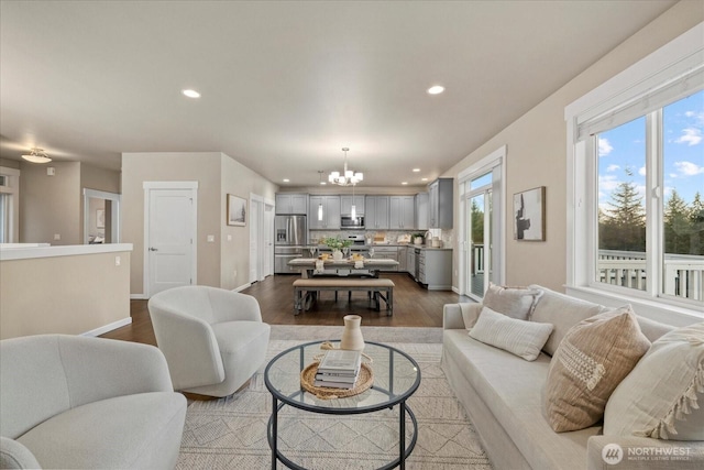 living room featuring an inviting chandelier, recessed lighting, plenty of natural light, and dark wood-style floors