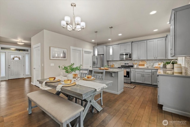 dining room with an inviting chandelier, recessed lighting, and dark wood-style flooring
