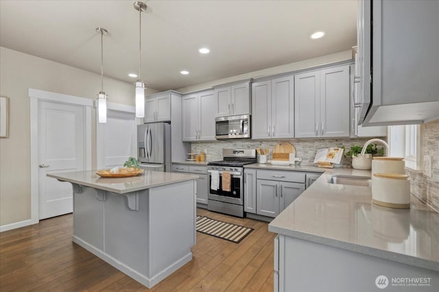 kitchen featuring a sink, light wood finished floors, stainless steel appliances, tasteful backsplash, and a kitchen island