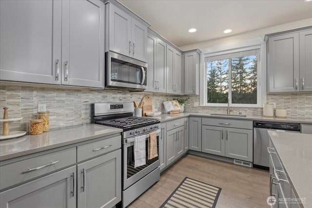 kitchen featuring a sink, gray cabinetry, stainless steel appliances, and light wood-style flooring
