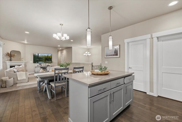 kitchen featuring dark wood-style flooring, a center island, light countertops, gray cabinets, and a chandelier