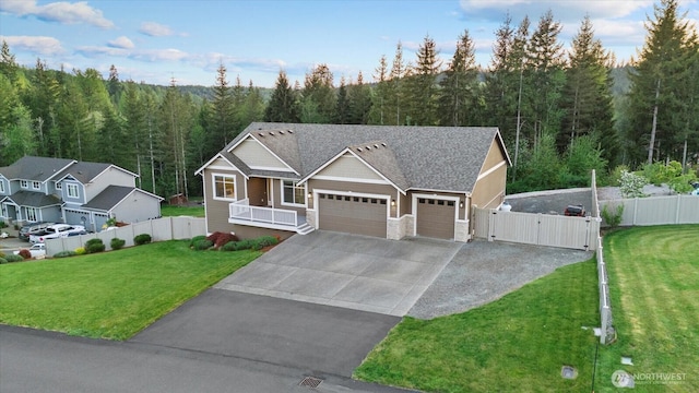 view of front facade featuring an attached garage, stone siding, a view of trees, a gate, and driveway