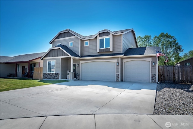 craftsman house featuring board and batten siding, driveway, a garage, fence, and stone siding
