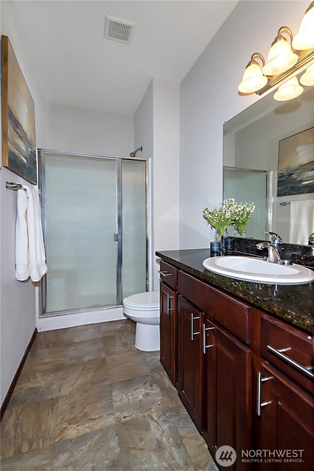 bathroom with visible vents, a shower stall, vanity, baseboards, and toilet