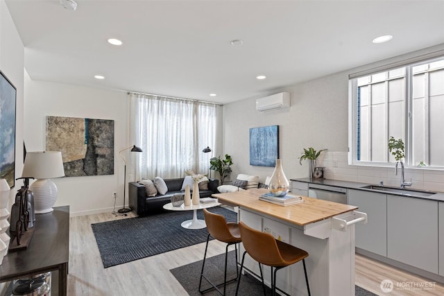 kitchen featuring a sink, a wall unit AC, a healthy amount of sunlight, and a kitchen bar