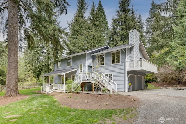 rear view of property with a garage, stairway, a chimney, covered porch, and driveway