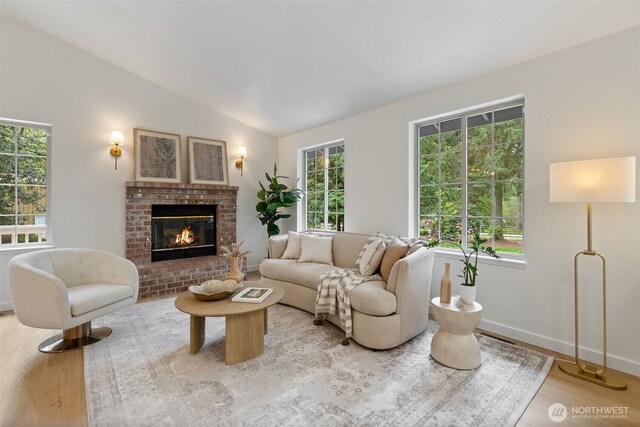 living room with baseboards, lofted ceiling, wood finished floors, and a fireplace