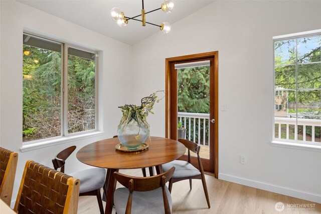 dining area with baseboards, a chandelier, lofted ceiling, and light wood-style floors