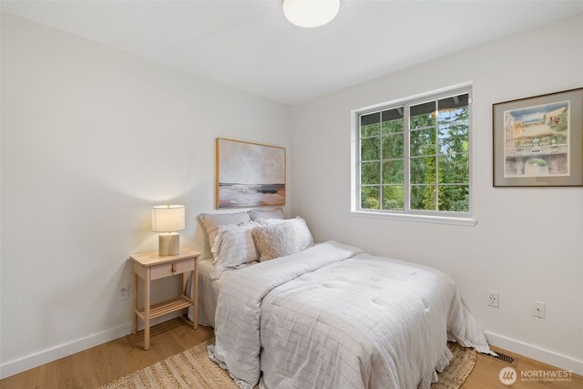 bedroom with baseboards, visible vents, and wood finished floors
