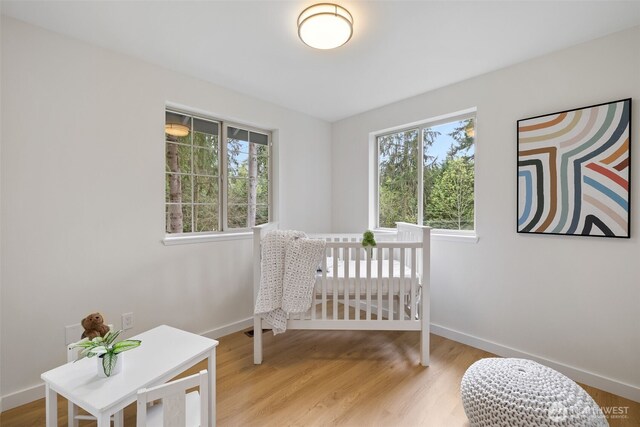 bedroom with baseboards, light wood-style floors, and multiple windows