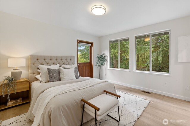 bedroom featuring baseboards, visible vents, and light wood finished floors