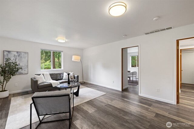 living room featuring baseboards, dark wood-type flooring, and visible vents