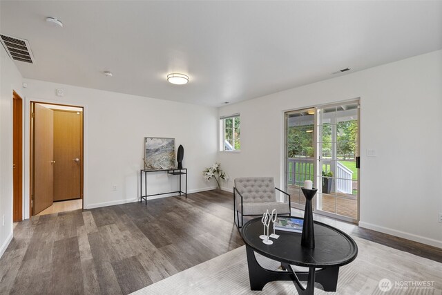 living area with visible vents, baseboards, and wood finished floors