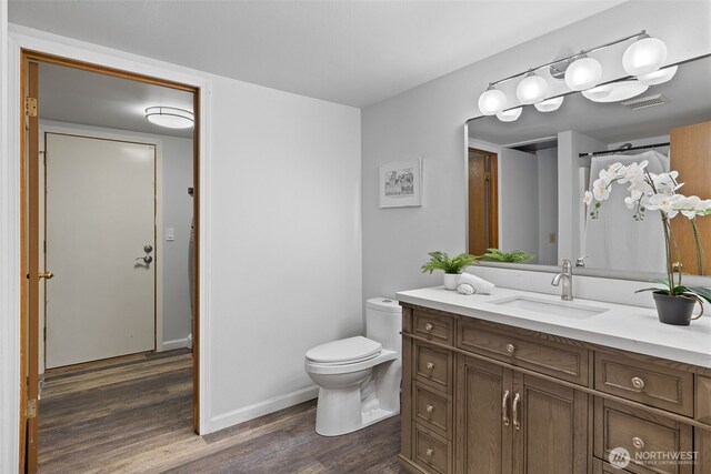 bathroom with visible vents, vanity, wood finished floors, toilet, and baseboards