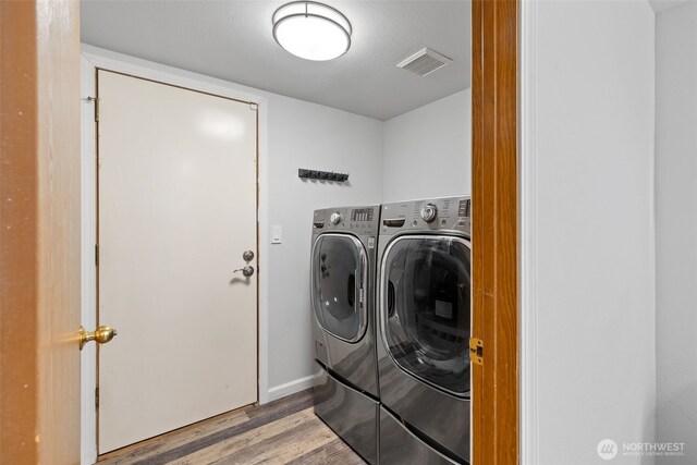 laundry room featuring washing machine and clothes dryer, laundry area, light wood-style floors, baseboards, and visible vents