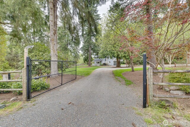 view of street with a gate, a gated entry, and gravel driveway