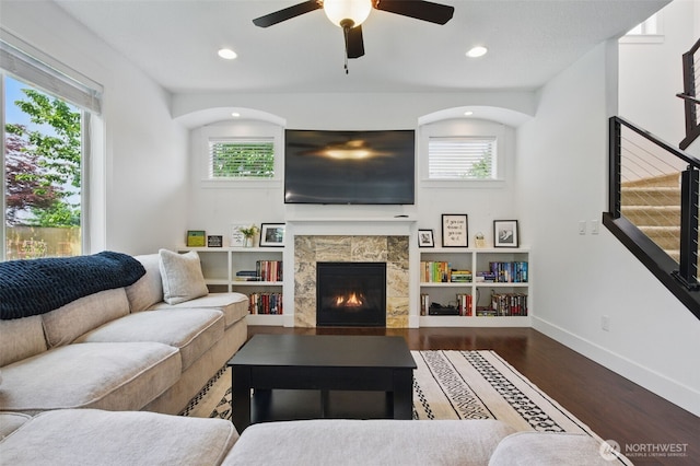 living area featuring plenty of natural light, a ceiling fan, wood finished floors, and a fireplace