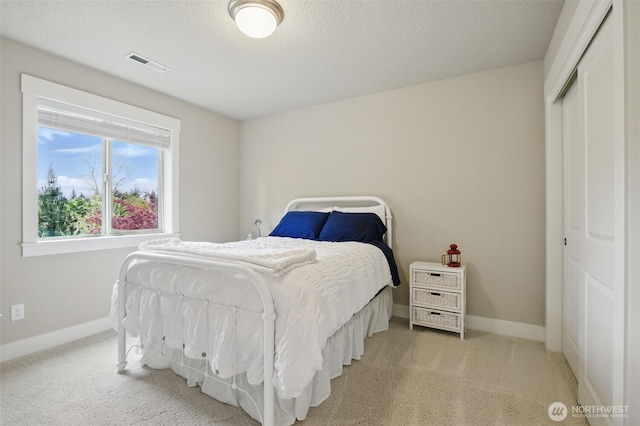 bedroom with light colored carpet, baseboards, visible vents, and a closet