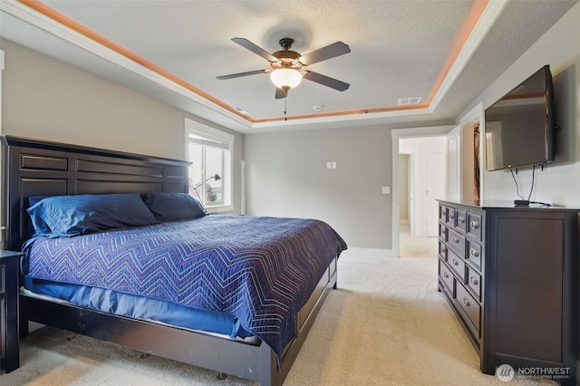 bedroom with visible vents, ceiling fan, a tray ceiling, and light carpet