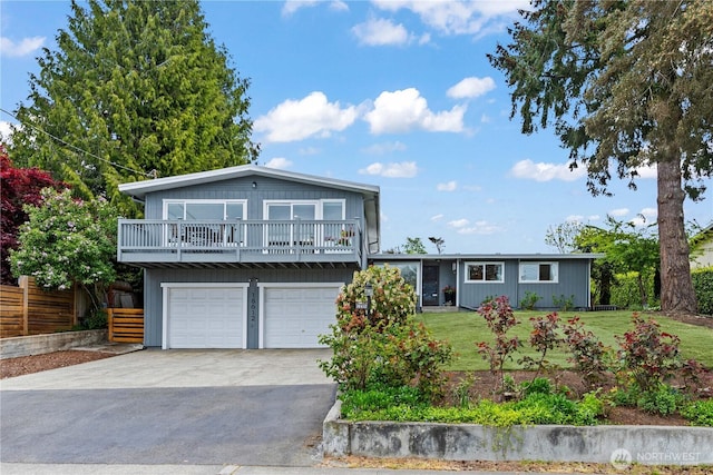 tri-level home with driveway, fence, a balcony, a front lawn, and an attached garage