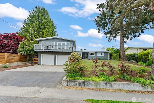 split level home with driveway, a front yard, a garage, fence, and a balcony
