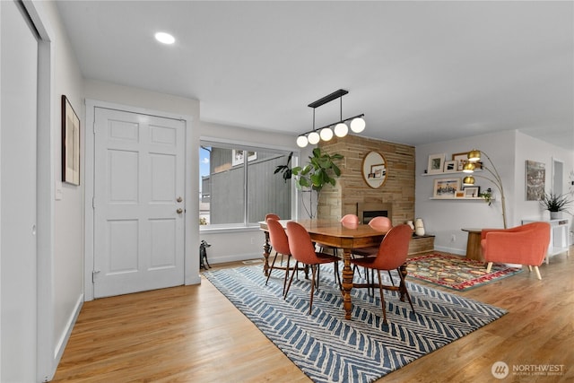 dining area featuring baseboards, light wood-style flooring, and a fireplace
